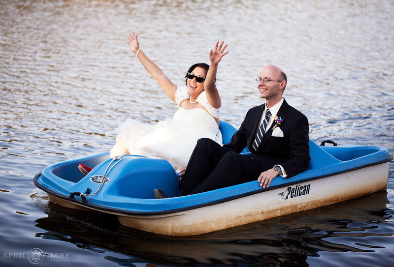 Adorable photo of bride celebrating with her arms in the air as she and her groom paddleboat into their wedding reception at the Evergreen Lake House