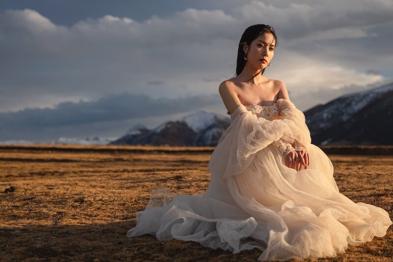 Couture dress bridal shoot on a field with mountains in the background and golden light.