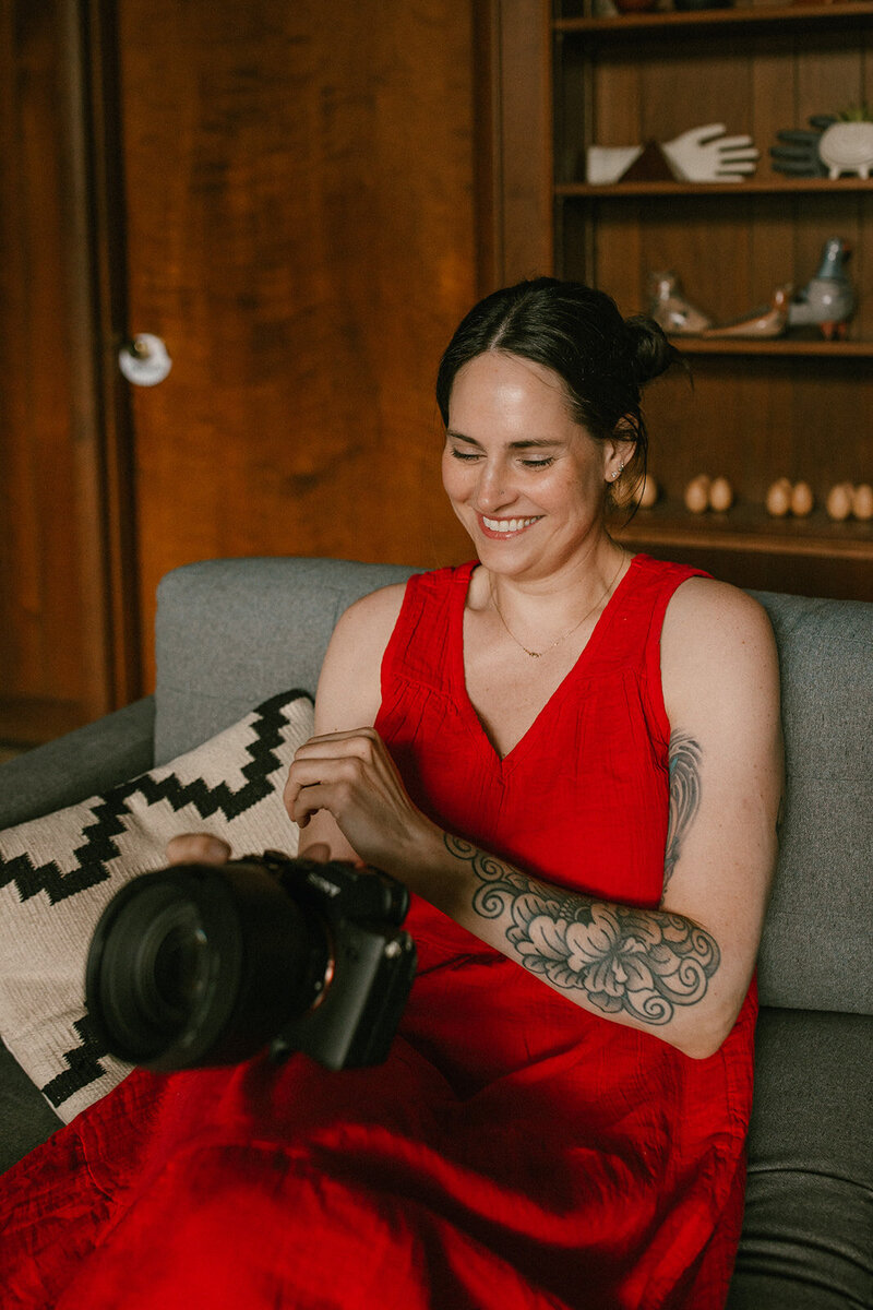 A woman holding a camera and looking at it while smiling