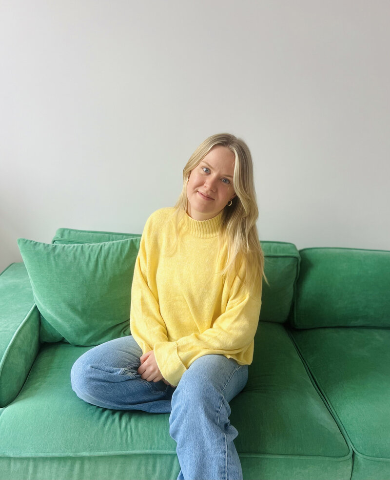 Sexual Counselor sitting on a green couch and smiling towards the camera