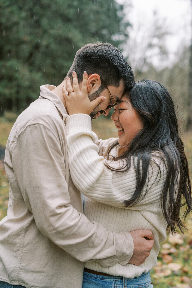 A couple embrace in the rain, representing an example of an engagement session by lifestyle photographer Among the Oaks. 