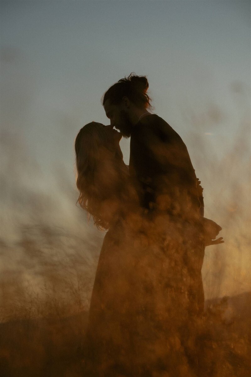 Couple standing on top of a mountain in New Hampshire at sunset, pointing out the scenery.
