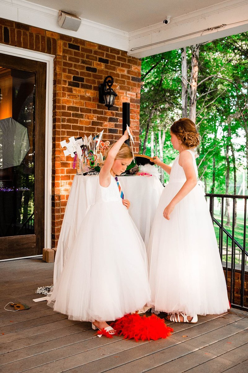 Flowergirls wearing tulle dresses and selecting props for their photobooth pictures