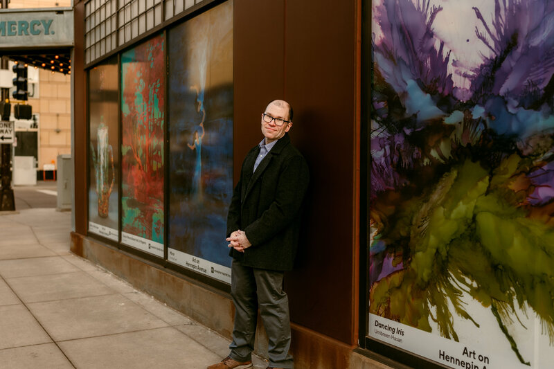Ryan leaning against a colorful mural in downtown Minneapolis during his dating profile photoshoot