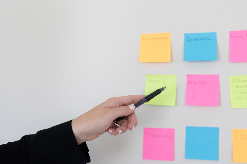 Becca pointing to colorful post it notes on a wall