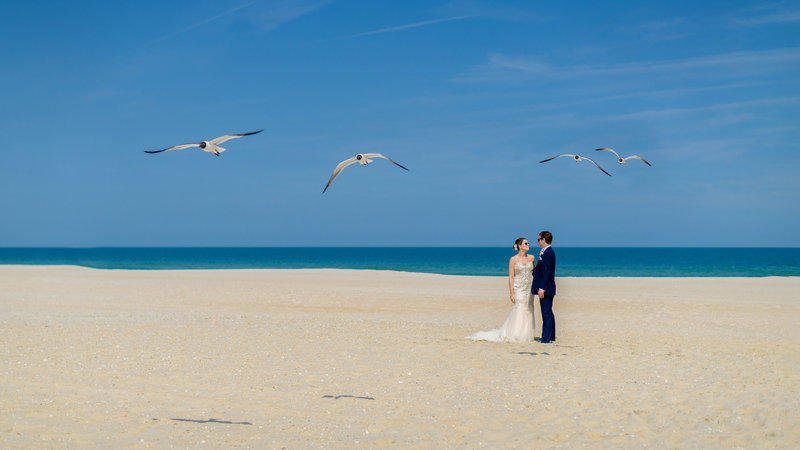 Bride and groom standing together on an empty beach at the New Jersey shore during their serene first look.