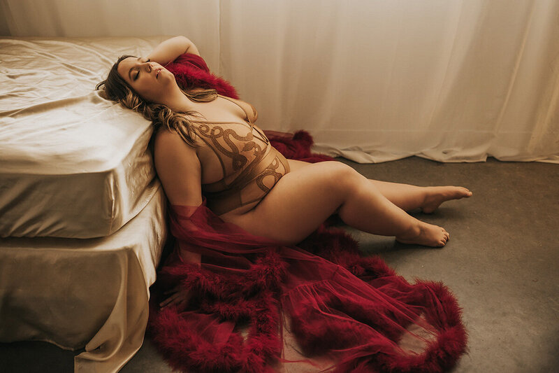 gorgeous boudoir client posing on chair in a black silk dress