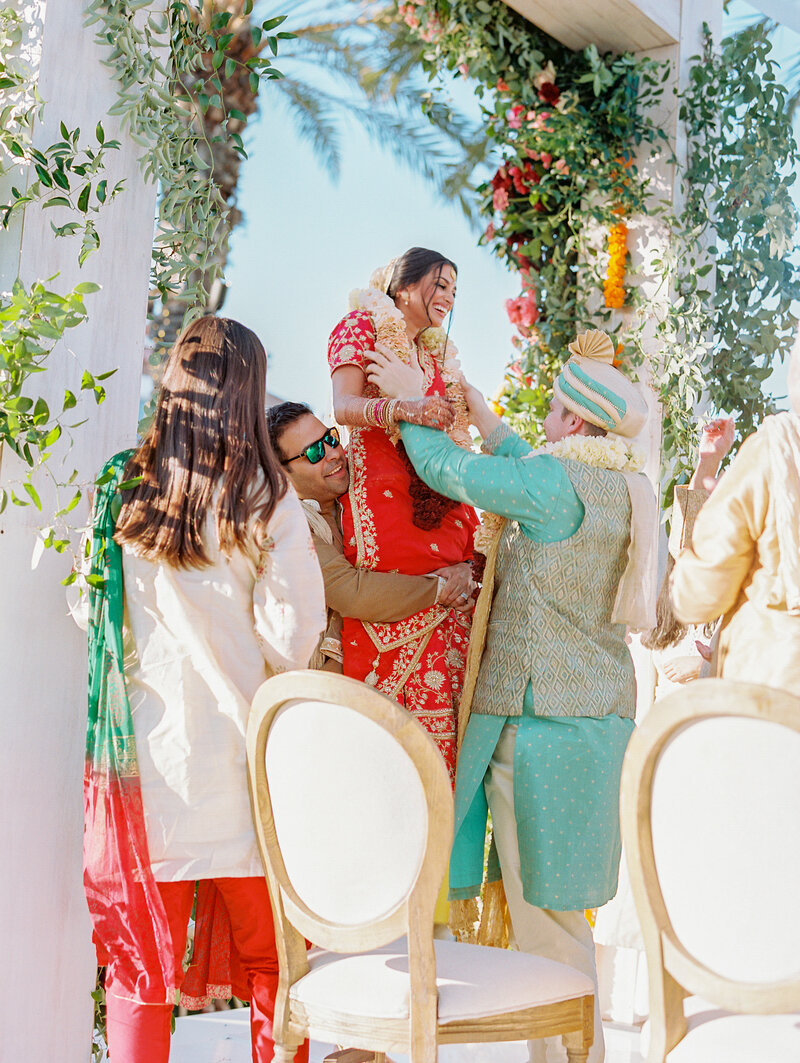 bride being lifted during indian ceremony  to greet groom before saying vows