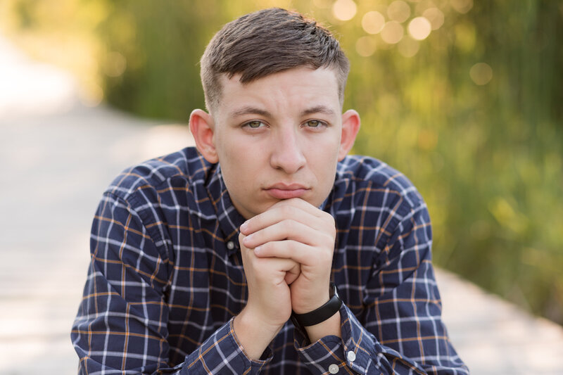 Senior boy seated on a boardwalk looking at the camera