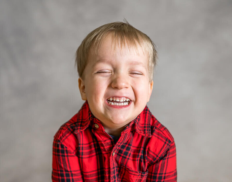 A child smiles so largely that their eyes are closed.