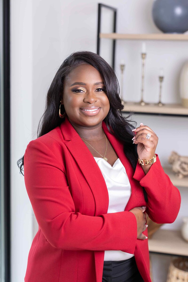 Creative headshot photographer in a red blazer posing in her office, featured in the Headshot Gallery Portfolio by Sophie K. Hunter in Dallas