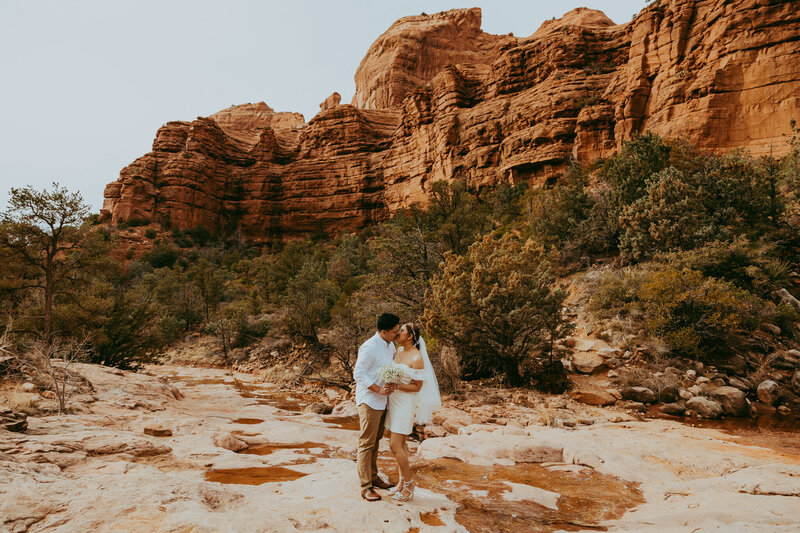 couple kissing in front of red rocks in sedona