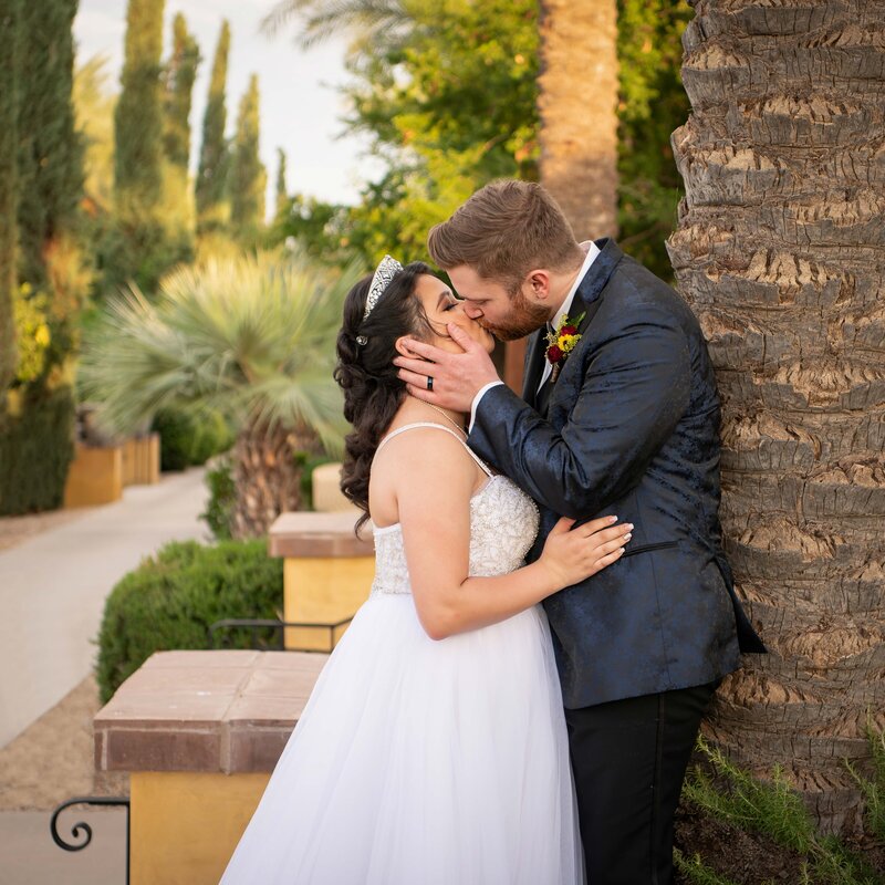 Bride and groom embrace and pose for portrait outside adobe building on their wedding day
