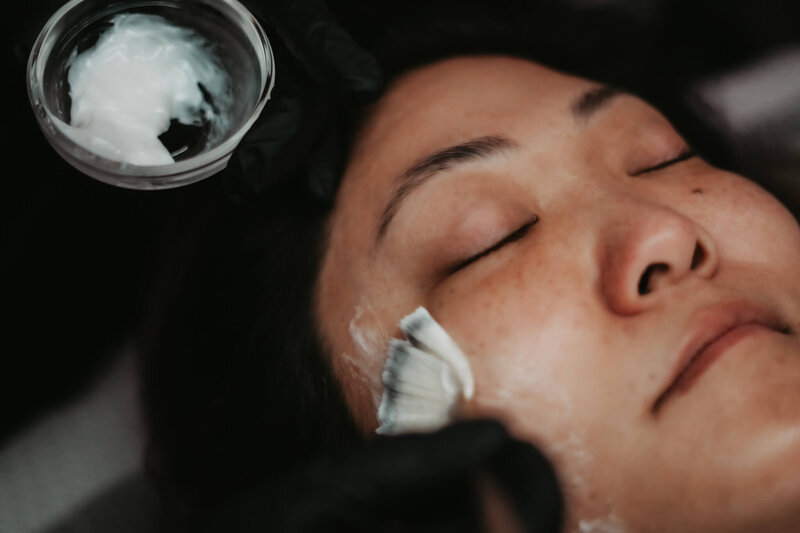 woman's face being brushed by an Esthetician for a basic facial. 