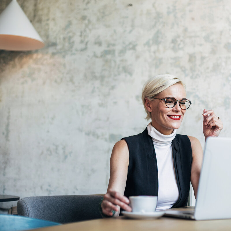 Female on a coaching zoom call smiling and holding a cup of coffee
