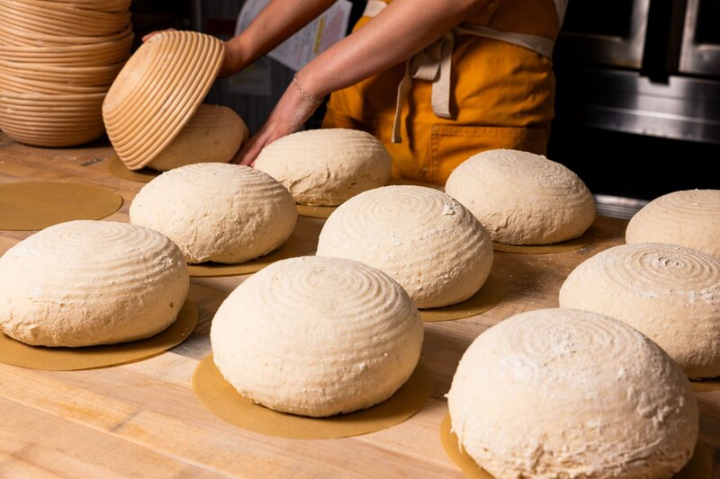 Baker shaping rounds of gluten-free sourdough bread at Grain Artisan Bakery in Snohomish, WA — representing their care for food allergies and transparent ingredient sourcing.