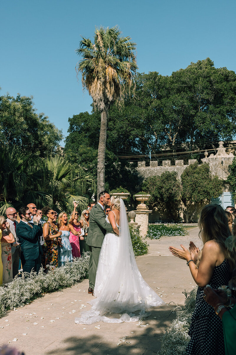 bride and groom kiss in the aisle at wedding in Malta