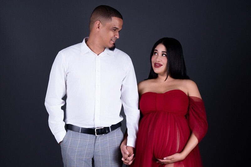 Couple maternity portrait with mom in a red dress and dad in white shirt