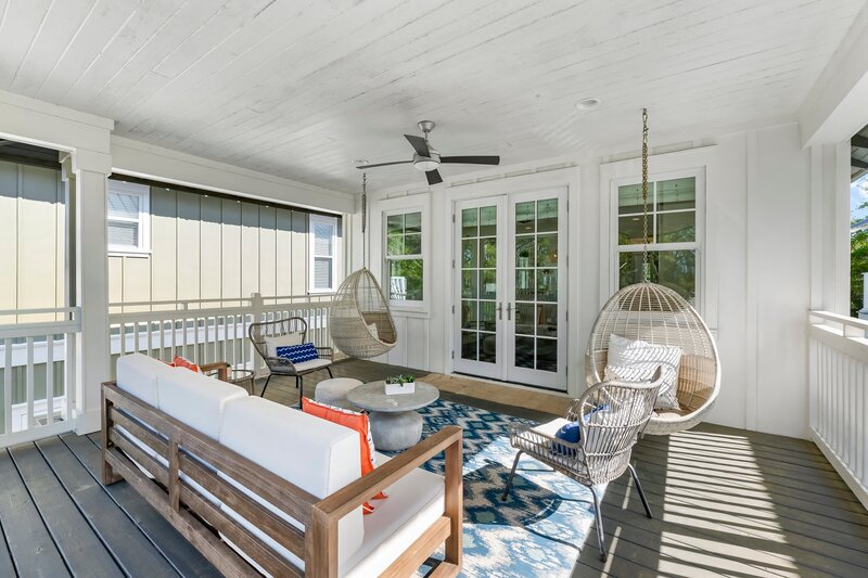Covered porch with egg chairs, sofa, and ceiling fan, ideal for lounging at Carillon Beach home