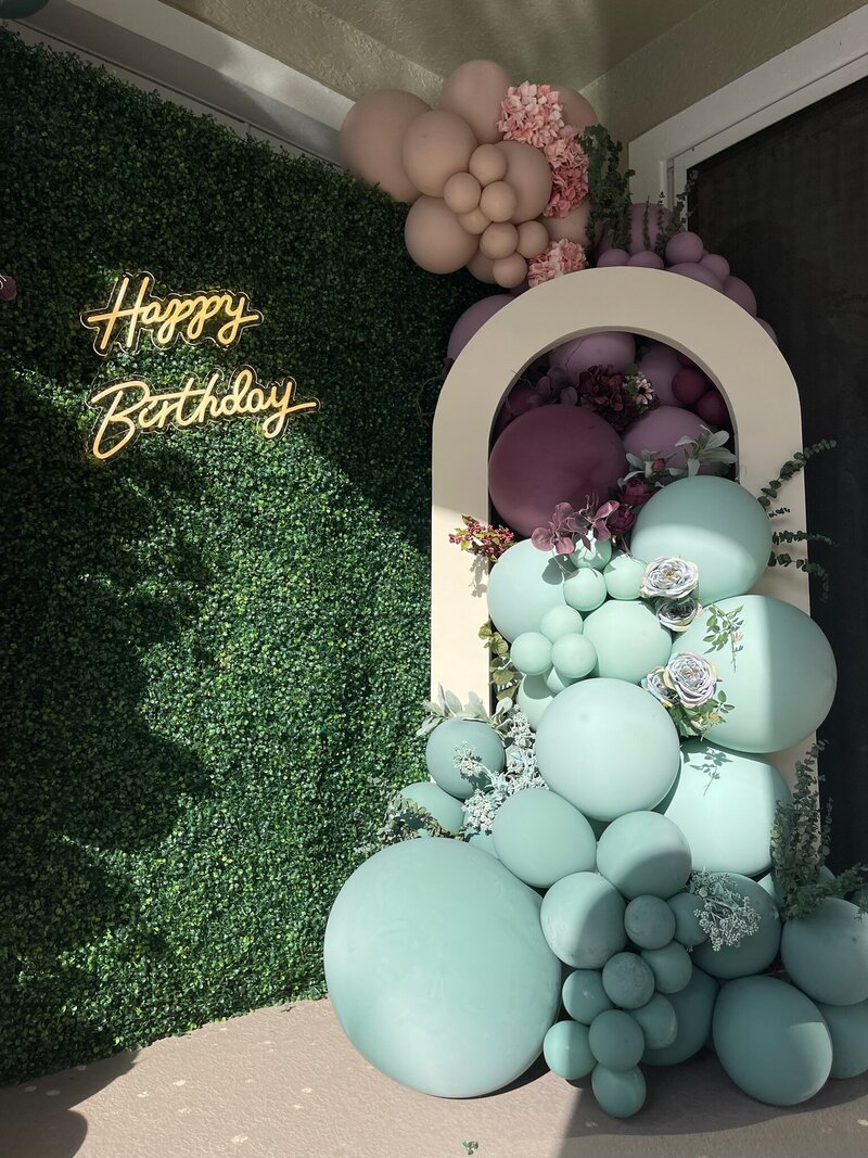 Balloon garland on a grass wall with a neon 'Happy Birthday' sign, styled by Loononna, LLC in Orlando, FL. Perfect for birthday party decor.