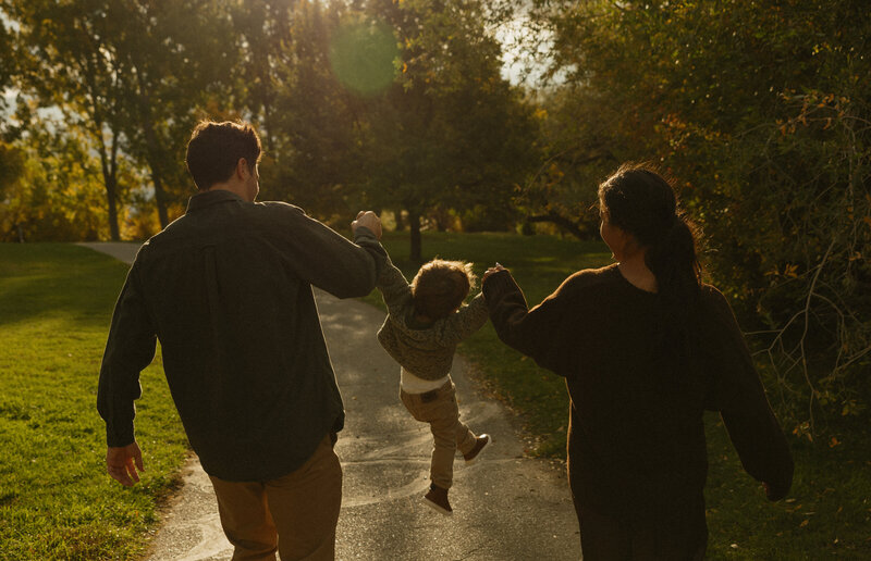 Candid family photo of a husband and wife building a mini snowman with their baby.