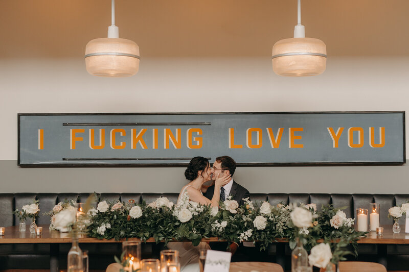 Couple kissing under sign that says "I fucking love you"