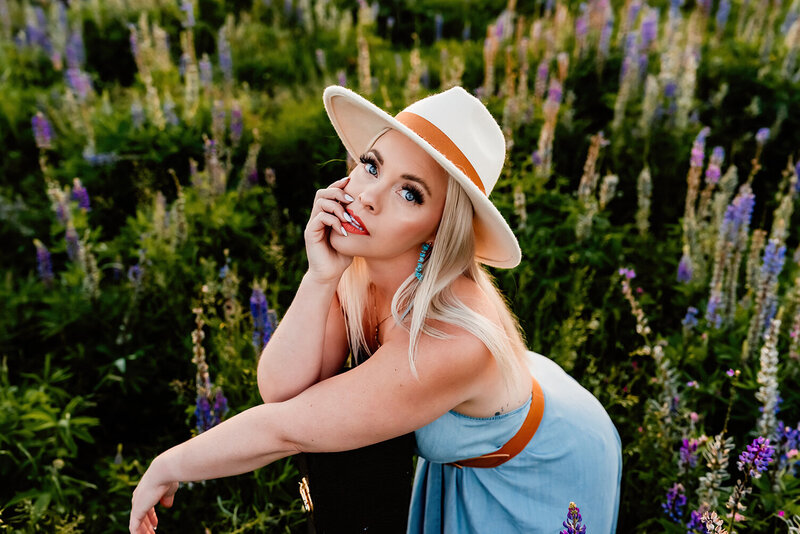 a country singer in a filed of lupines with her guitar