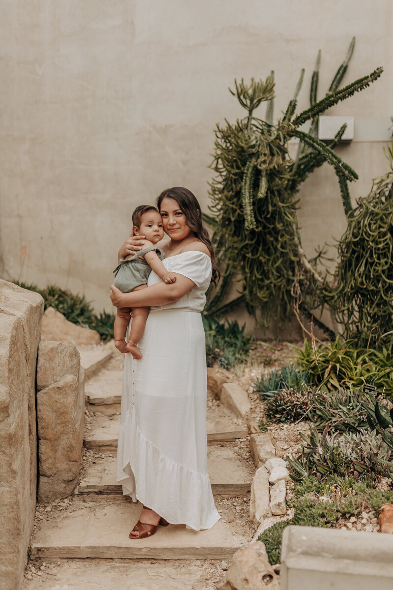A mom holding her newborn during at the San Antonio Botanical Garden steps. Taken by family San Antonio photographer.