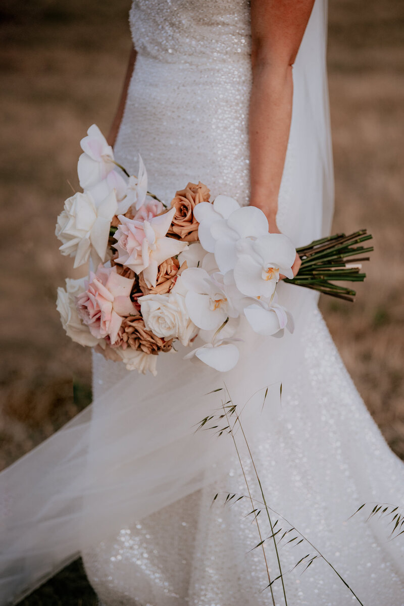 Close up of bridal bouquet containing roses and singapore orchids.