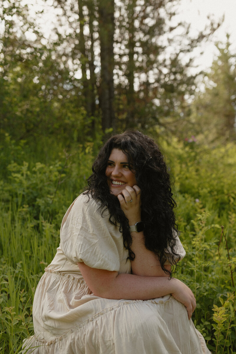 Brigette holding her camera and looking slightly over her shoulder at the camera, holding a neutral face.