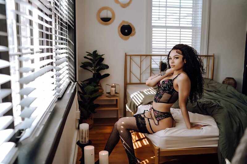 Woman sitting on the edge of bed for sultry boudoir portrait