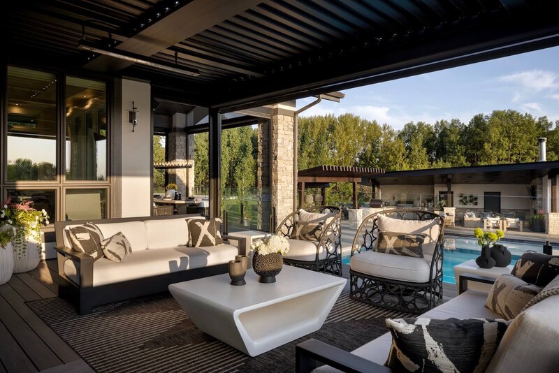 An outdoor living space with black and white accents and suncoast enclosure overlooking a large pool. 