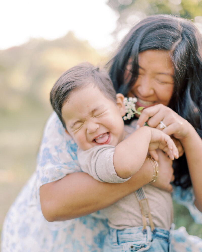 Mom tickles young son's ears with a flower during family portrait session