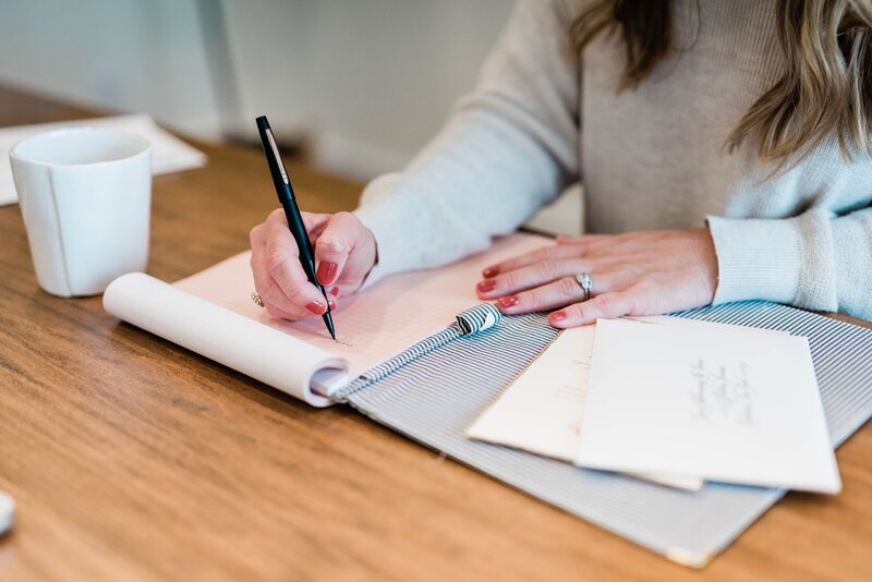 Custom stationery business owner writing down notes about client's event.