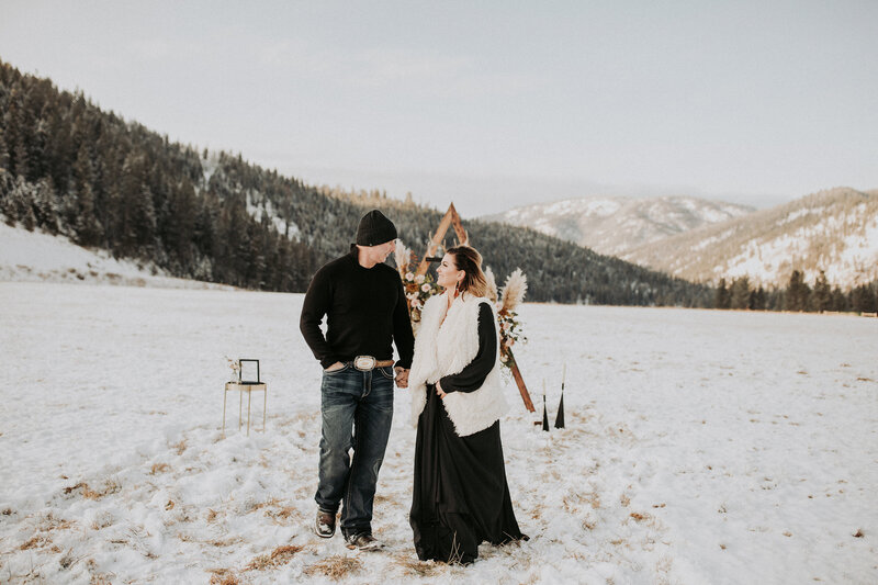An elopement couple hold hands and walk in the snow
