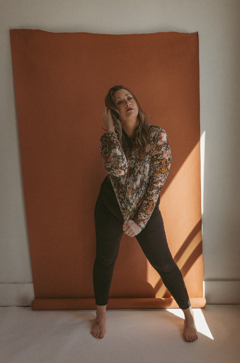 Kayla Pontier posing in front of an orange wall.