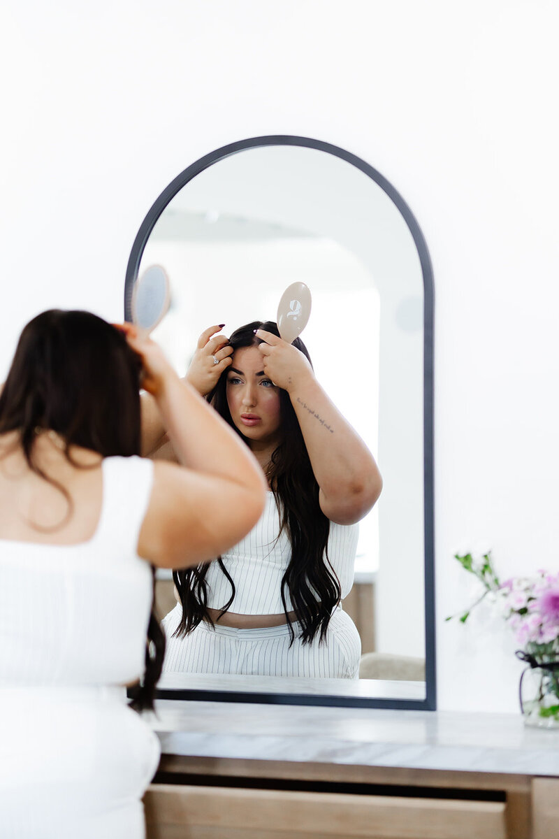 Lexi looking in mirror and fixing her hair