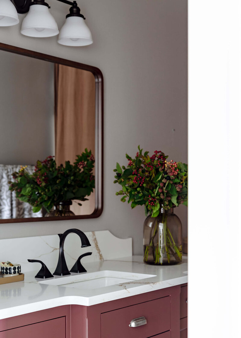 A bathroom vanity with quartz counter and sink and a large mirror hanging above it representing a modern farmhouse interior design.