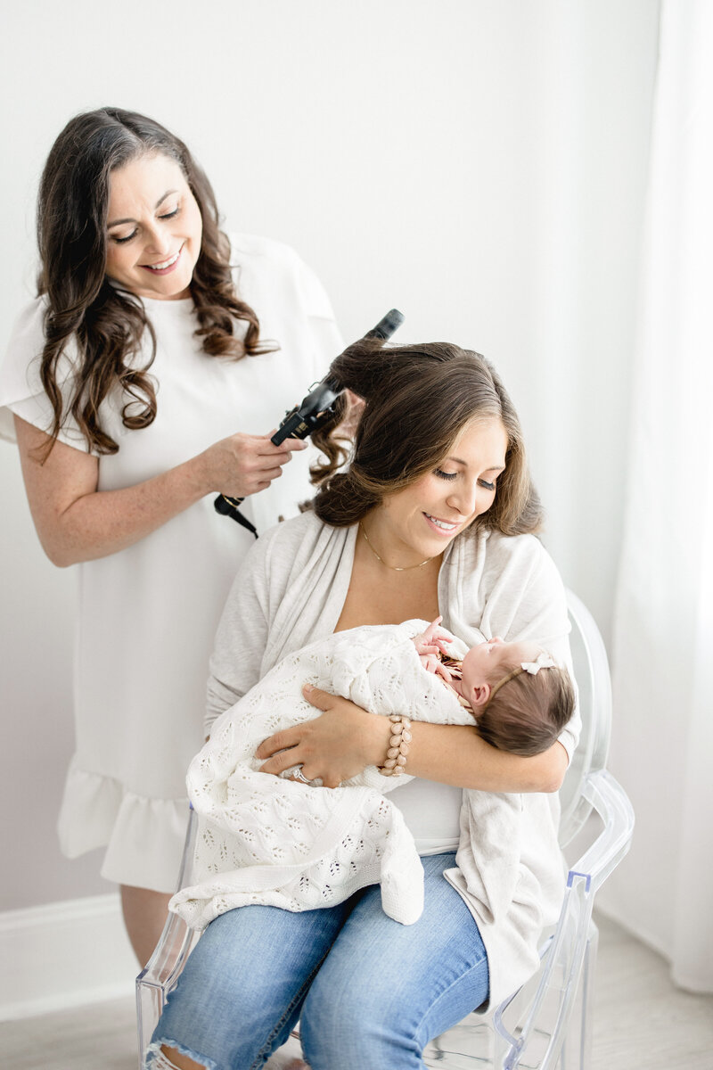 New mom holding newborn getting hair and make up done for newborn photography with Marie Buck Photography.