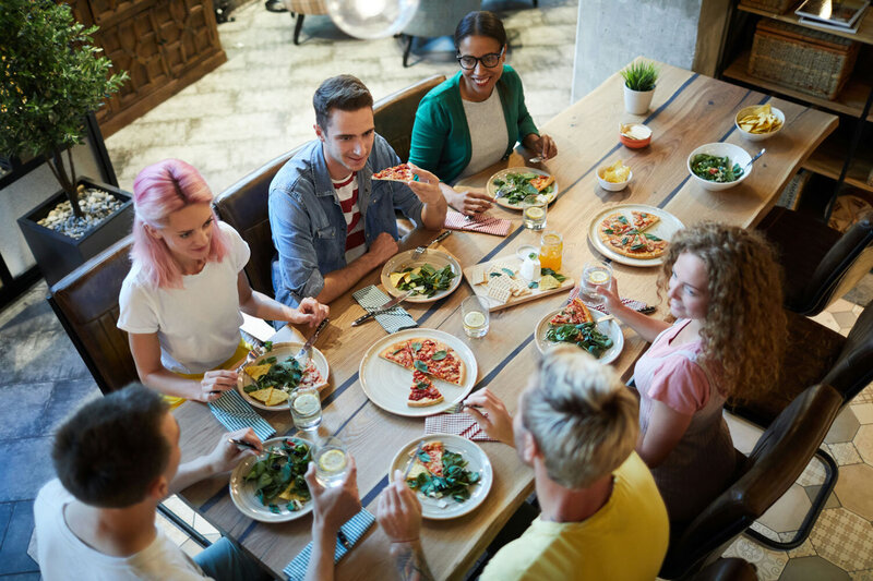 group of people eating pizza at table