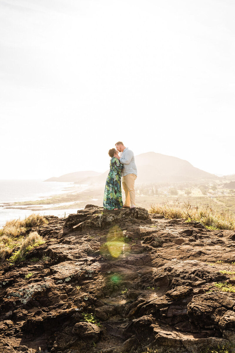 couple kissing on oahu cliff at sunset