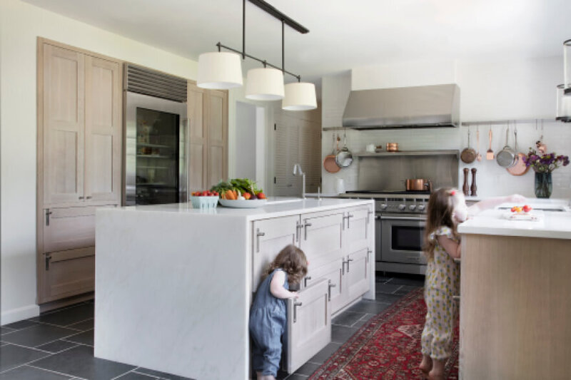 Westwood kitchen designer creates a natural oak kitchen with white counters, a waterfall marble island, stainless steel appliances, and slate flooring with a vintage runner.