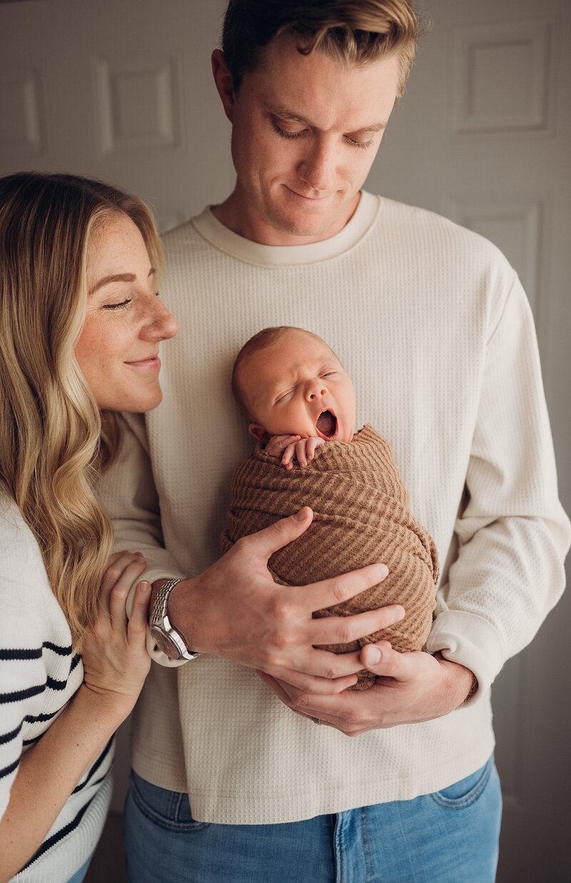 new dad holding newborn baby in his nursery