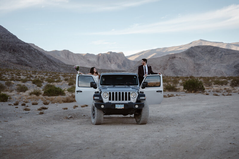 A couple climbs into a silver Jeep smiling big after saying their vows