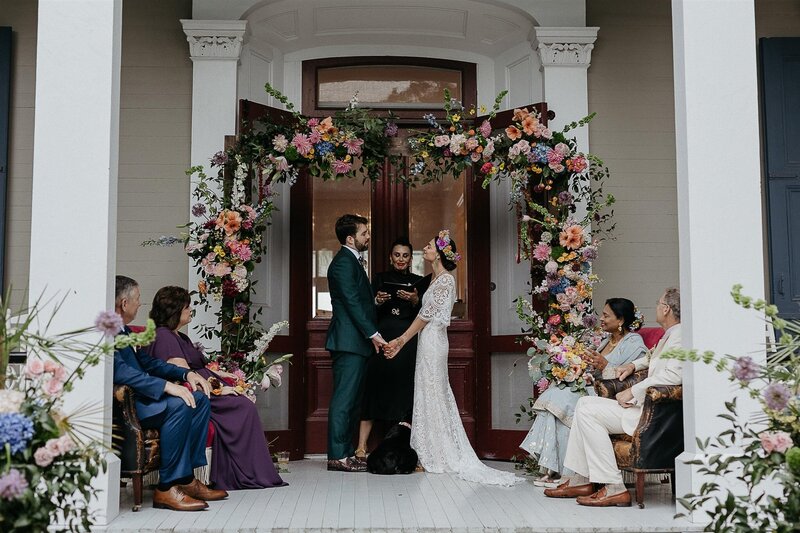 Camille and Justin stand underneath a floral arch.