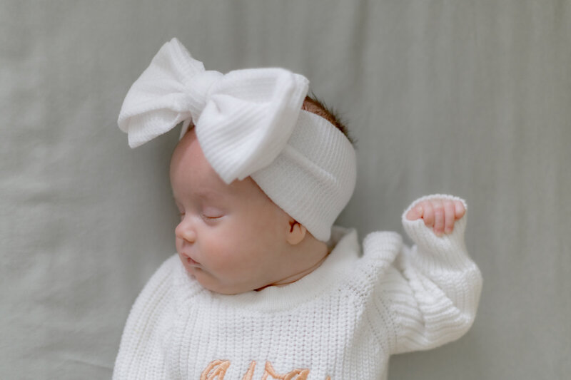 newborn lifestyle baby girl with bow in crib sleeping in louisville ky