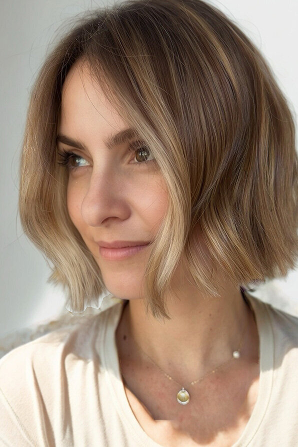 Soft, textured bob haircut with warm caramel highlights, styled with a natural finish for a polished look.