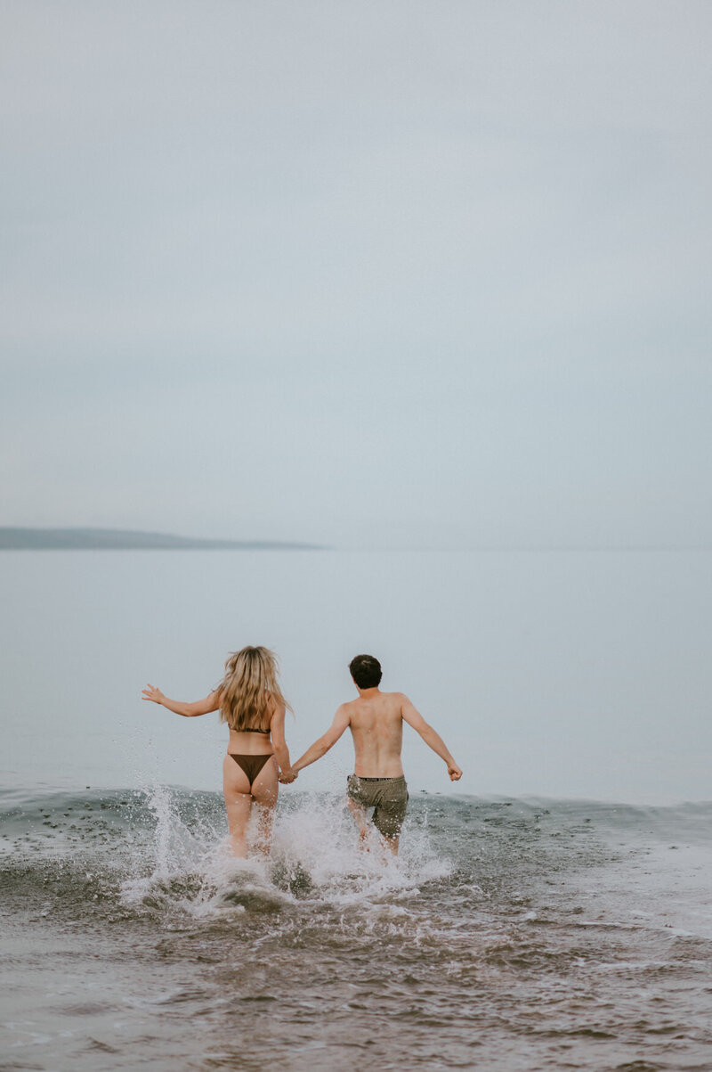 couple running into the waves at a beach in Maui