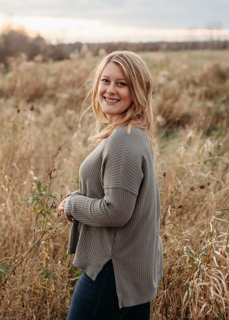 Chiropractor Brittany Fisk smiling in a natural outdoor setting during fall, symbolizing warmth and wellness.