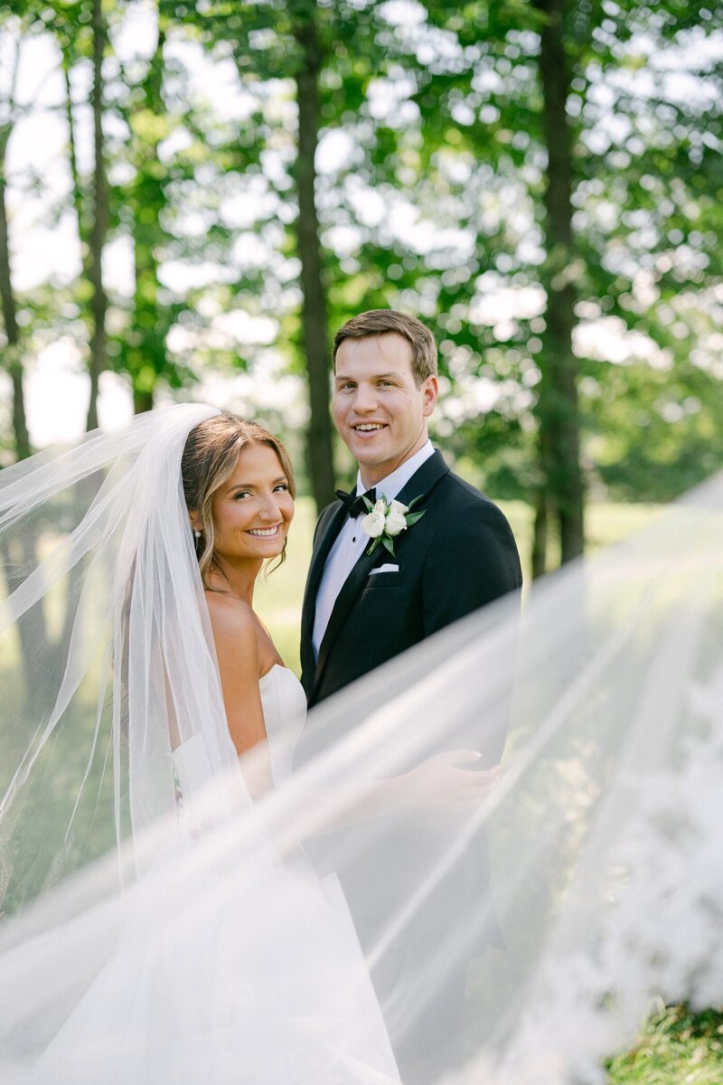 Anya and George smiling through her veil among the trees